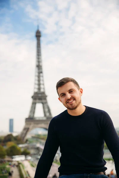 Hombre alegre en jersey azul oscuro está de pie en el fondo de la Torre Eiffel — Foto de Stock