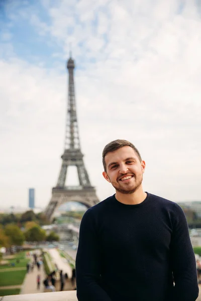 stock image Cheerful man in dark blue pullover is standing on the background of the Eiffel Tower