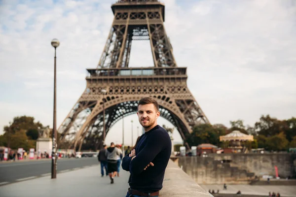 Hombre guapo en jersey oscuro está de pie en el fondo del puente de la Torre Eiffel — Foto de Stock