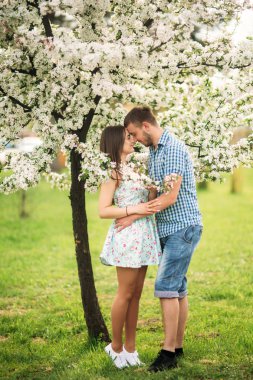 Çiçek Bahçe dinlenme aşık genç bir çift. beyaz çiçek açan ağaçlar