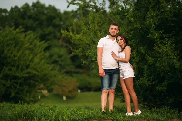 Citas en el parque. Pareja de amor de pie juntos en la hierba cerca del lago. Romance y amor — Foto de Stock