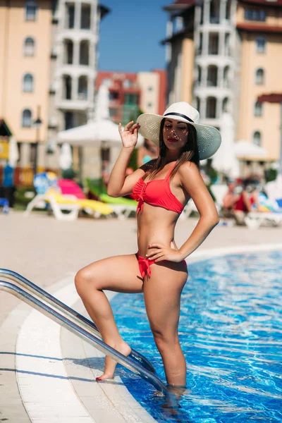 Una dama sexy en un sombrero de playa grande salir de la piscina —  Fotos de Stock