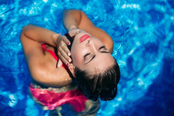 Fotosesión de moda de una chica sexy con maquillaje en un traje de baño rosa. Vista desde arriba —  Fotos de Stock