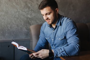 Bir kafede bir kitap okuma sakallı yakışıklı adam