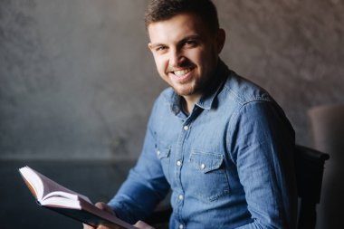 Bir kafede bir kitap okuma sakallı yakışıklı adam