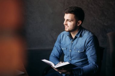 Bir kafede bir kitap okuma sakallı yakışıklı adam