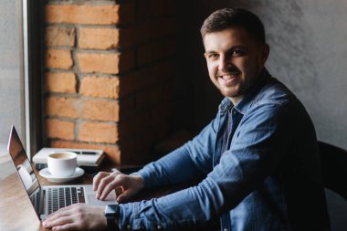 Bir sakallı bir dizüstü bilgisayar bir kafede kullanır.