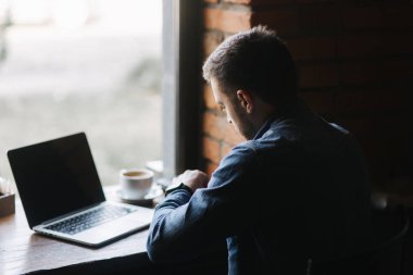 Bir sakallı bir kafe ve saati göz bir dizüstü bilgisayar kullanarak