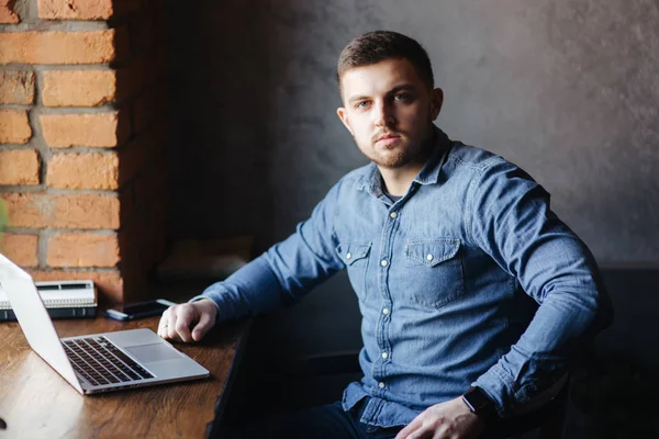 Bir sakallı bir dizüstü bilgisayar bir kafede kullanır.