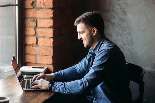 Bir sakallı bir dizüstü bilgisayar bir kafede kullanır.