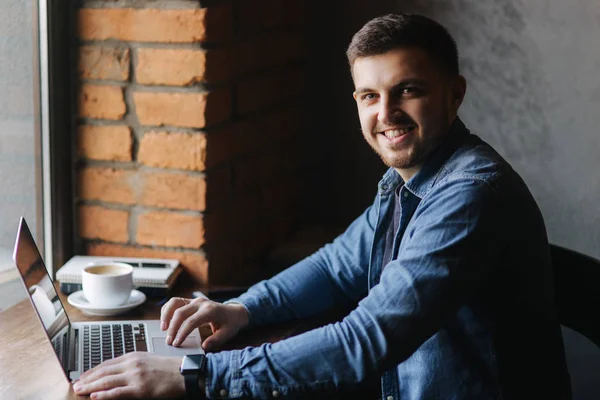 Bir sakallı bir dizüstü bilgisayar bir kafede kullanır.