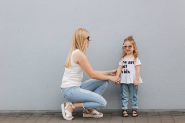 Anne ve kız açık havada şehirde. oynamak ve eğlenmek. Moda mutlu anne ve çocuk kızı şehirde birlikte eğleniyor