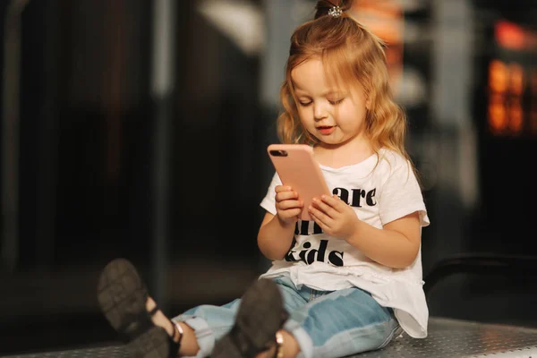 Holčička je posezení na lavičkách a použití telefonu — Stock fotografie