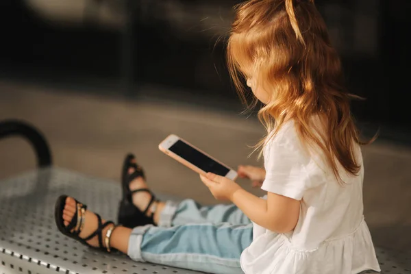 Holčička je posezení na lavičkách a použití telefonu — Stock fotografie