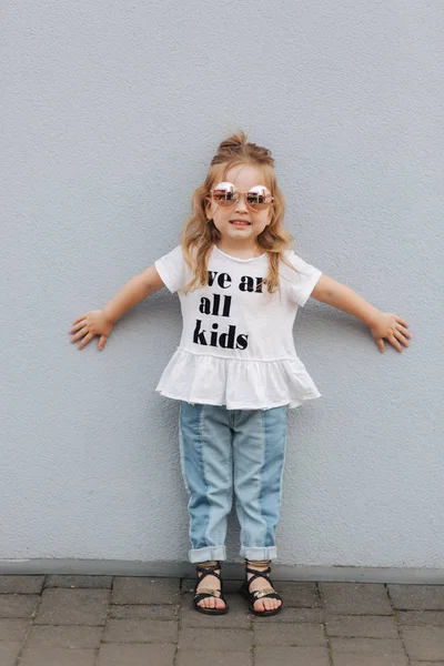 Kleines Mädchen probiert Sonnenbrille an und posiert für Fotograf — Stockfoto