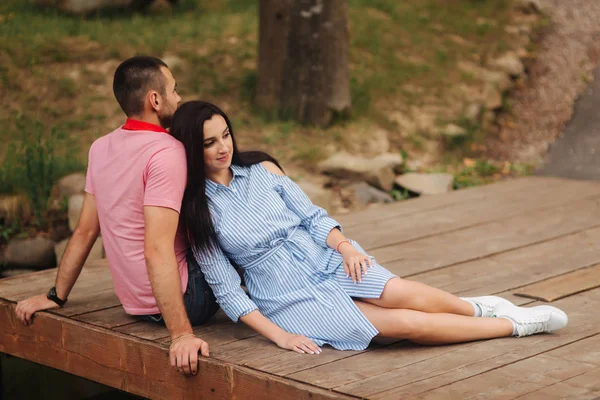 Nádherný pár v parku u jezera, sedět na molu — Stock fotografie