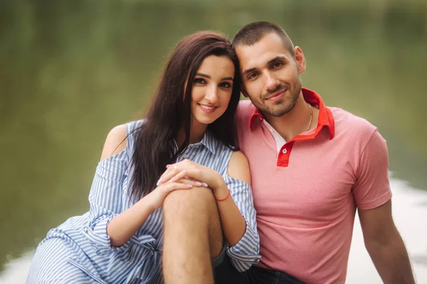 Hermosa pareja caminando en el parque cerca del lago, sentarse en el muelle — Foto de Stock