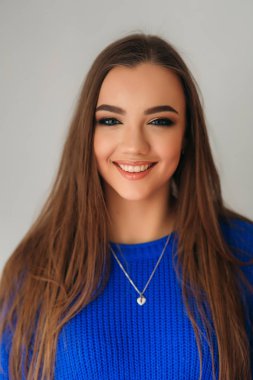 Güzel esmer kız mavi bir bluz bir fotoğrafçısına poz ve ona makyaj gösteren güzel bir gülümseme