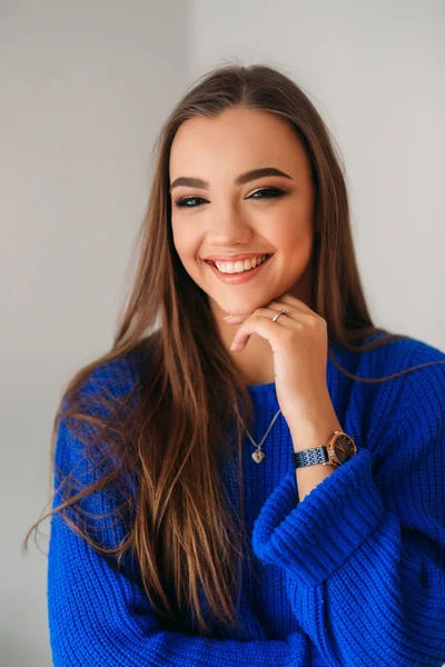 Güzel esmer kız mavi bir bluz bir fotoğrafçısına poz ve ona makyaj gösteren güzel bir gülümseme