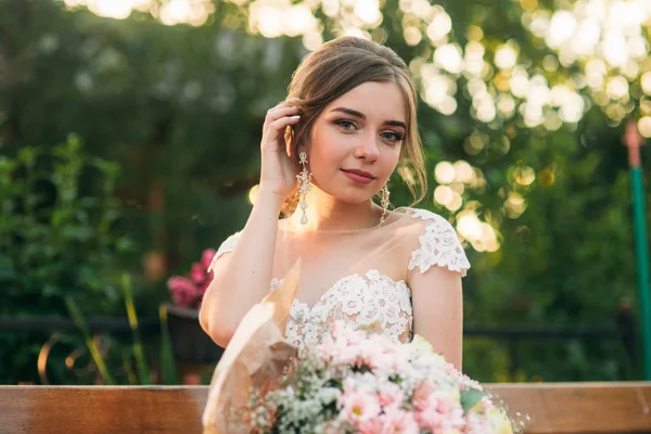 Молодая девушка в свадебном платье в парке позирует для фотографа — стоковое фото