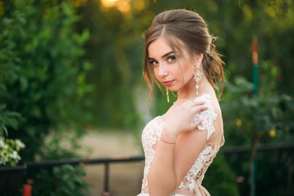Молодая девушка в свадебном платье в парке позирует для фотографа — стоковое фото