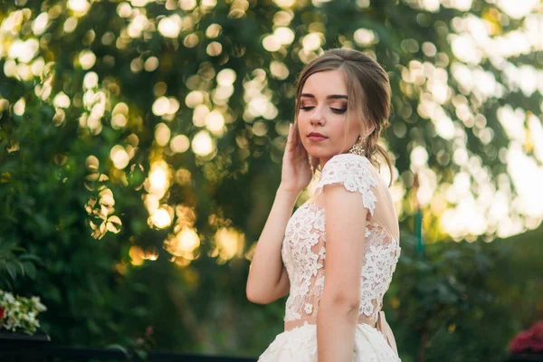 Jovem em vestido de noiva no parque posando para fotógrafo — Fotografia de Stock