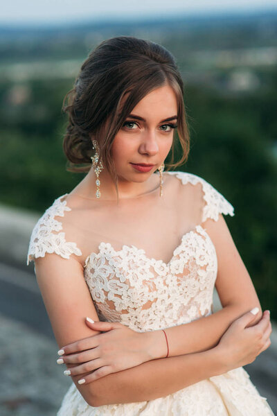 Teenage girl in wedding dress on city. Background town sunset