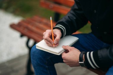 Bir öğrenci bir siyah ceketli bir parkta oturur düşüncelerini bir defter aşağı bir Bank yazıyor. Yakışıklı çocuk