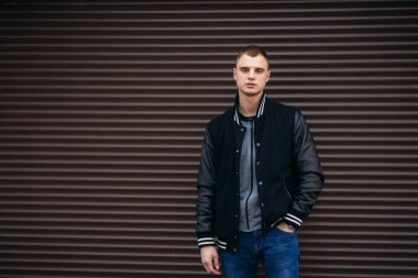 Bir arka plan koyu çizgili duvar siyah ceketli genç bir çocuk