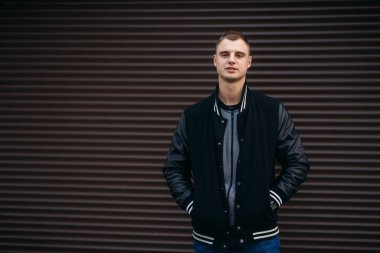 Bir arka plan koyu çizgili duvar siyah ceketli genç bir çocuk