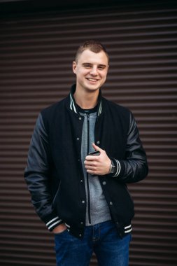 Bir arka plan koyu çizgili duvar siyah ceketli genç bir çocuk telefon kullanır