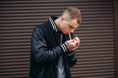 Bir arka plan koyu çizgili duvar siyah ceketli genç bir çocuk duman Sigara