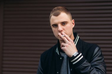 Bir arka plan koyu çizgili duvar siyah ceketli genç bir çocuk duman Sigara