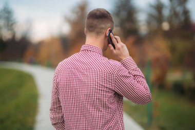 Bir telefonu kullanarak bir ekose gömlekli şık adam