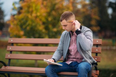 Sevimli öğrenci tezgah yazıyor onun notebool bir pensil kullanarak onun düşüncelerinde aşağı oturur