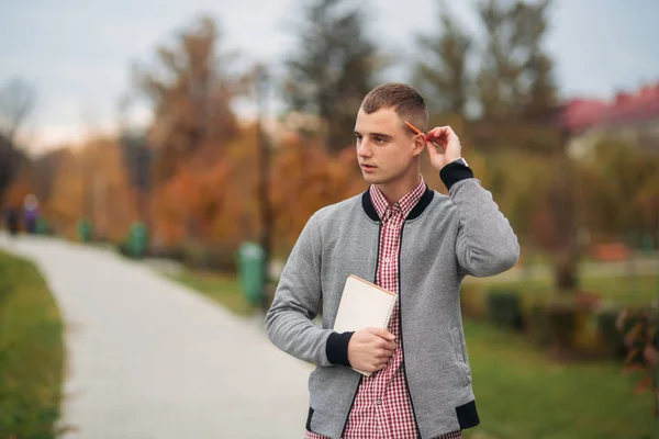 Un estudiante lindo escribe sus pensamientos en su notebool usando un pensil — Foto de Stock