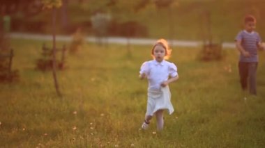 Küçük erkek ve kız çalıştırmak ve yürütmek. Karahindiba patlattılar