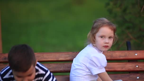 Ragazzo mangiare un gelato e seduto sulla panchina mentre la ragazza è alla ricerca — Video Stock