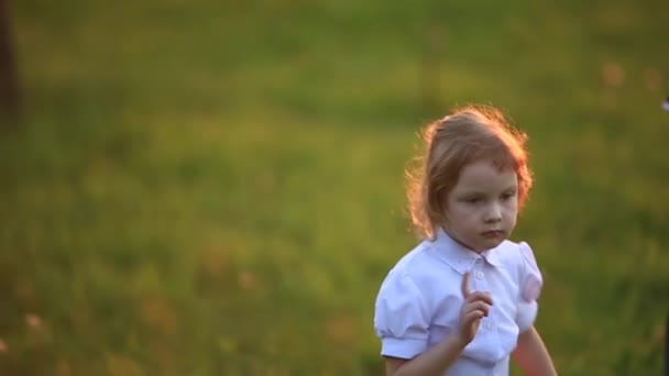 El niño y la niña corren y juegan. Soplan diente de león — Vídeos de Stock