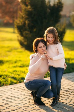 Küçük kız annesi ile sonbaharda parkta yürüyüş bluz giymiş. Altın sonbahar.