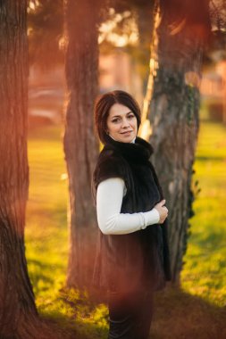 Genç bir anne parkta altın sonbaharda yürür.