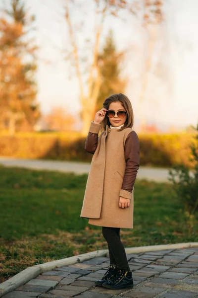 Dziewczynka w jesienny płaszcz pozowanie dla fotografa. Złota Jesień — Zdjęcie stockowe