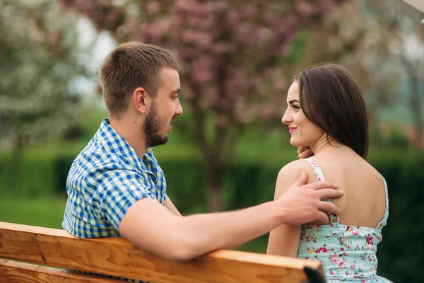 Mladý pár v lásce odpočinku v rozkvetlé zahradě. bílý kvetoucí stromy — Stock fotografie