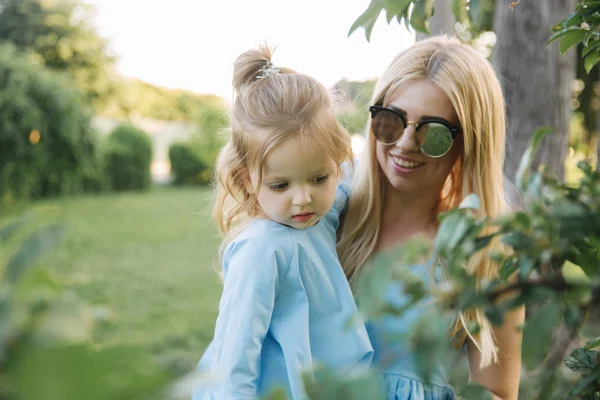 Küçük sevimli kızıyla birlikte genç güzel kadın. Genç Kızı Anne yaz parkta hugs.