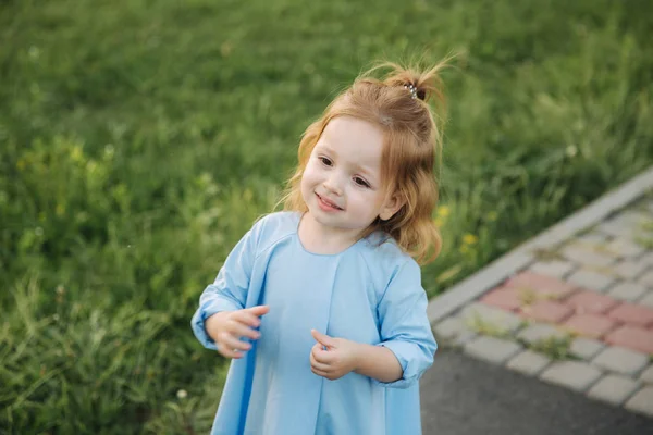 Kleines Mädchen in blauem Kleid spaziert durch Park — Stockfoto