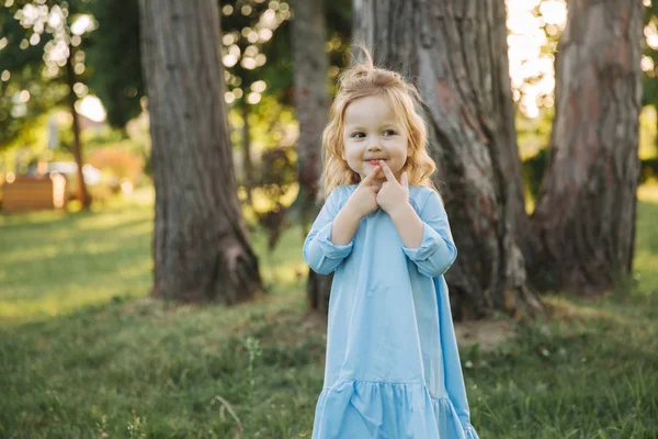 Маленькая девочка в синем платье прогулка в парке — стоковое фото