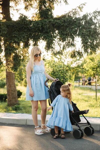 küçük kızı anne bebek arabası itme yardımcı olur.