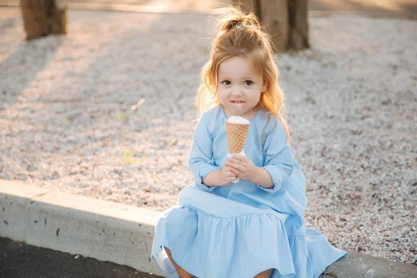 아이스크림을 먹는 파란 드레스에 아름 다운 소녀 — 스톡 사진