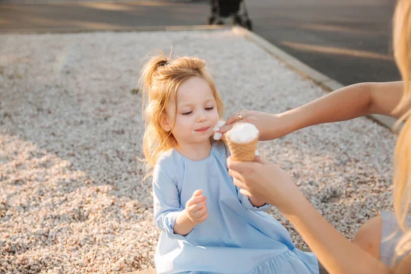 穿着蓝色连衣裙的漂亮小女孩吃冰淇淋, 妈妈帮她擦嘴。 — 图库照片
