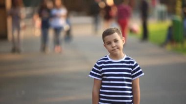 Çizgili bir gömlek içinde küçük bir çocuk gülümseyen ve tezahürat. Bahar, güneşli havalarda